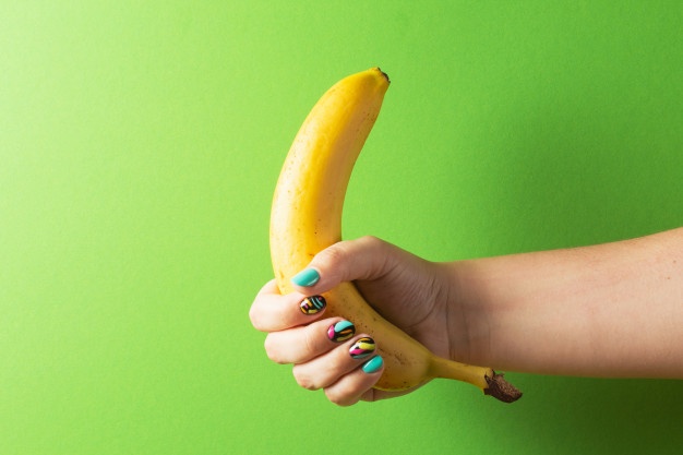 female-hand-with-colorful-manicure-holding-banana-on-green-background_168892-292.jpg